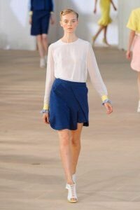 Юбка тюльпан синего цвета с запахом от Preen 2012 с полупрозрачной белой блузкой Preen и ботильонами белого цвета Preen