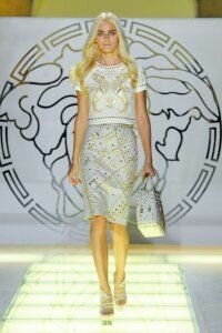 Юбка-карандаш светло-серого оттенка с золотым набивным теснением от Versace 2012 с белым укороченным топом с золотым принтом Versace и босоножками светло-серого цвета на высоком каблуке Versace