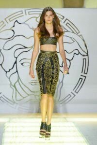 Юбка-карандаш из чёрной кожи с золотым набивным теснением от Versace 2012 с коротким топом чёрно-зелёных тонов со змеиным принтом Versace и зеленовато-чёрными босоножками на высоком каблуке и платформе Versace